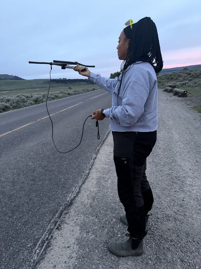 Taylor holding up a radio telemetry antenna beside a road
